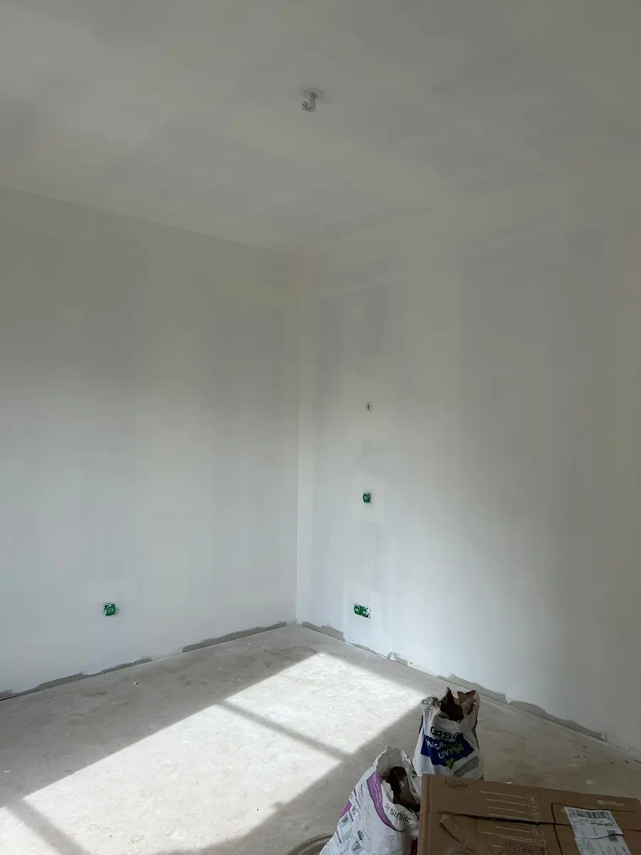 Angle de pièce après préparation des murs, avec des boîtiers électriques visibles.