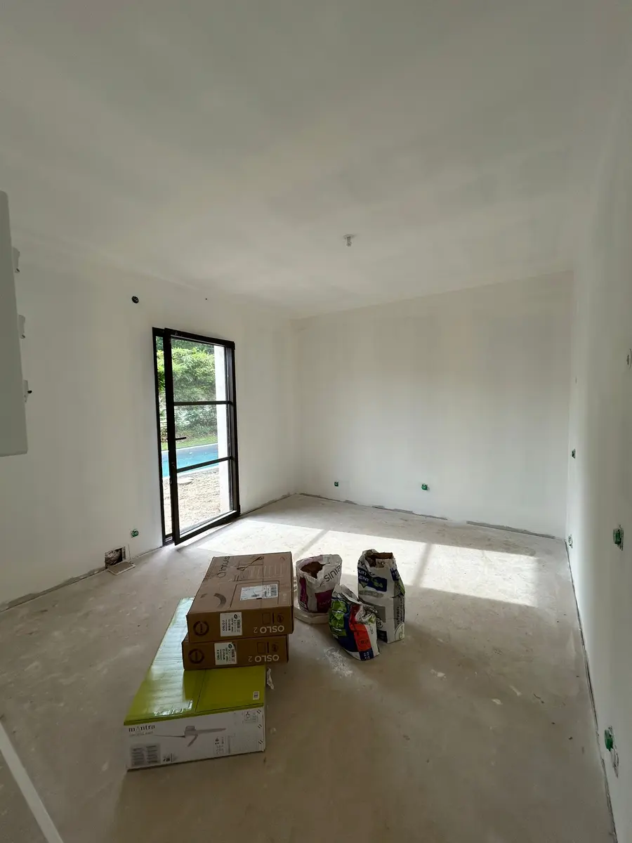 Pièce en cours de finition avec des seaux et des cartons au sol.