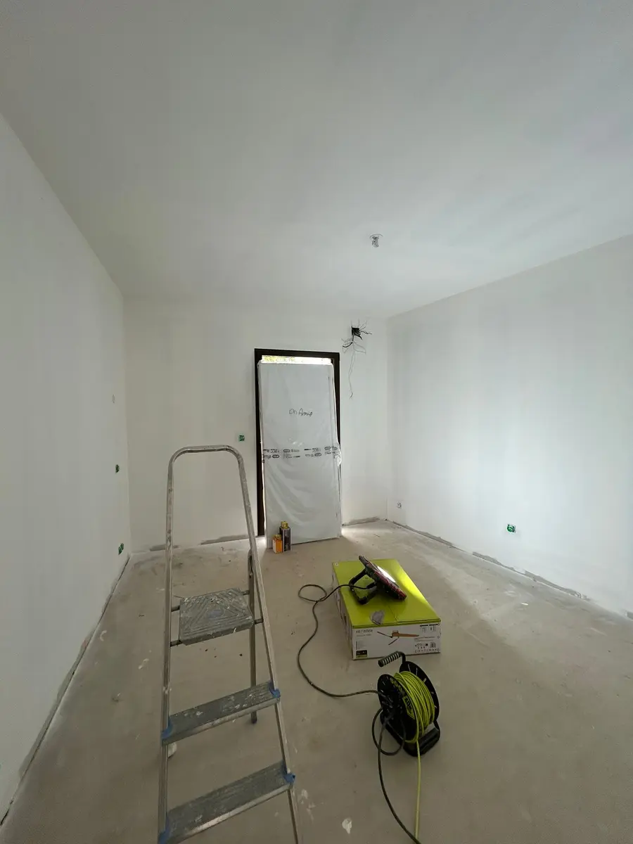 Longue pièce aux murs préparés, avec un escabeau et un appareil de chantier.