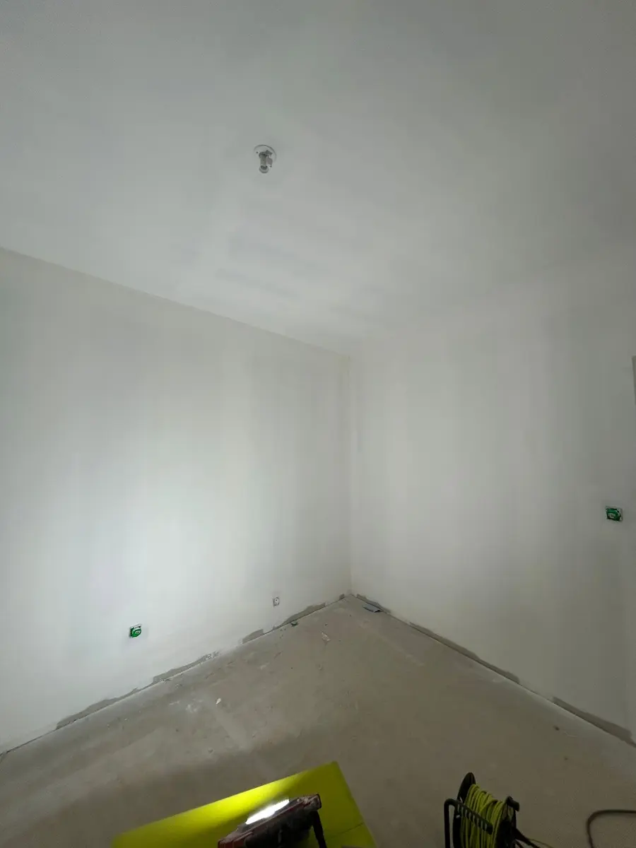 Mur et plafond préparés dans une pièce au sol brut.