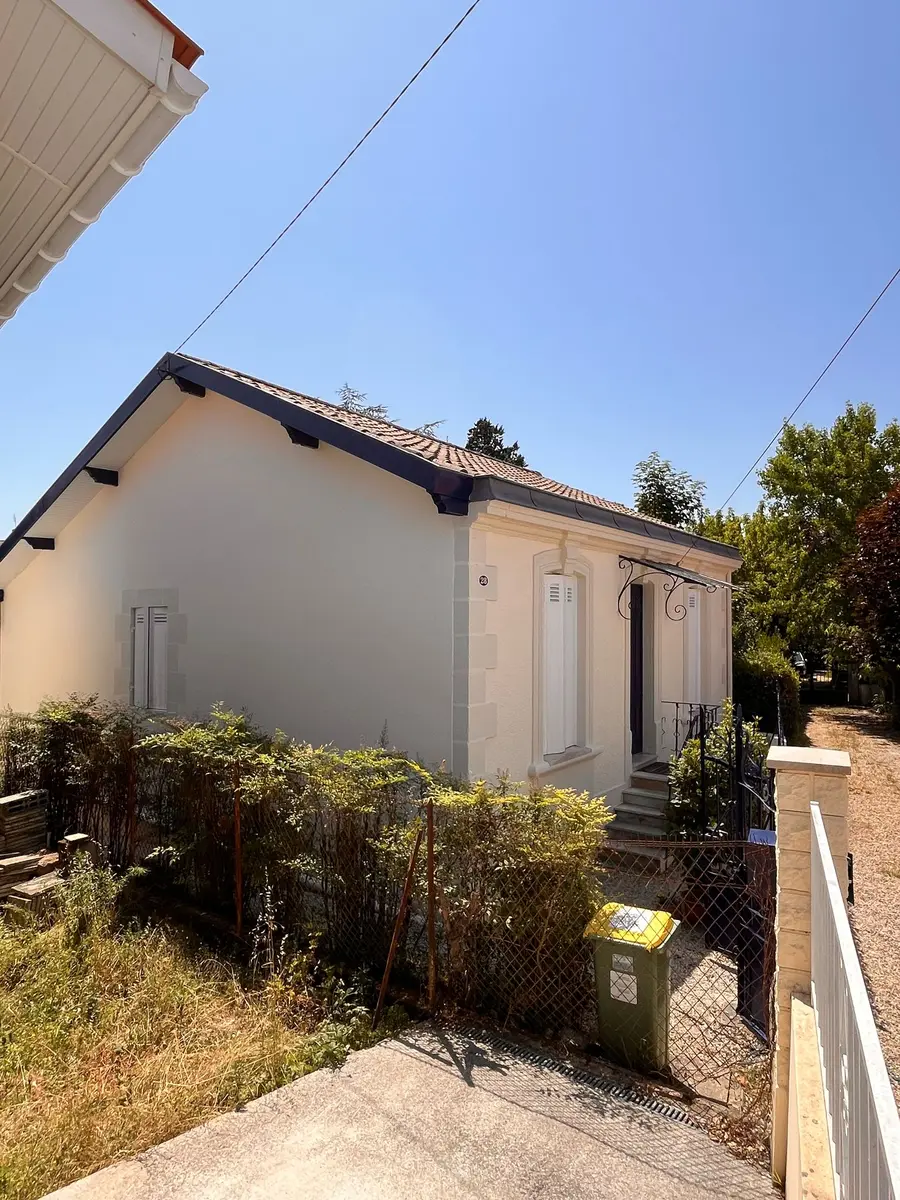 Pignon et façade latérale d’une maison claire, vus depuis le jardin.