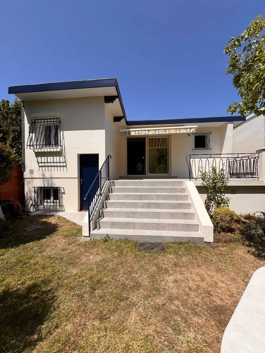 Façade côté jardin avec un escalier blanc et une terrasse.