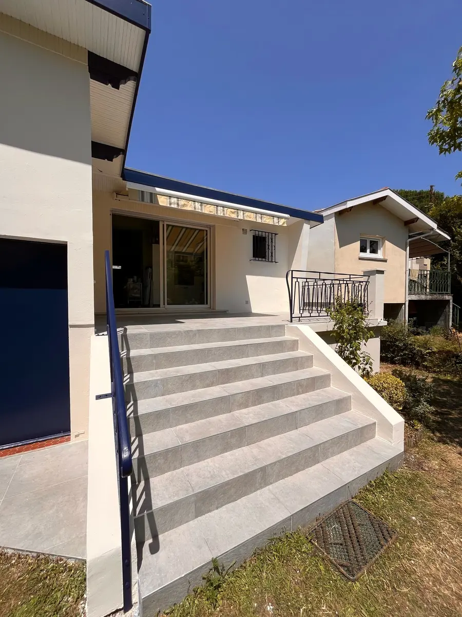 Vue rapprochée de l’escalier blanc et de la terrasse d’une maison.