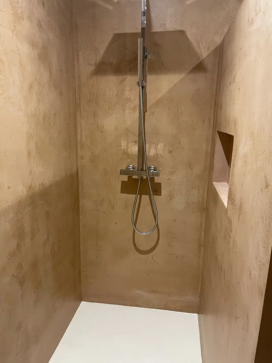 Douche avec des murs beiges nuancés et une robinetterie murale.