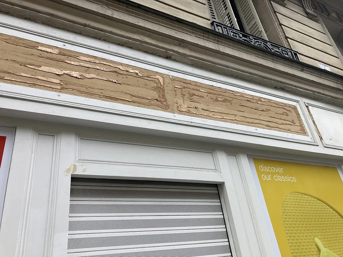 Détail d’une devanture avec des moulures et un panneau décapé.
