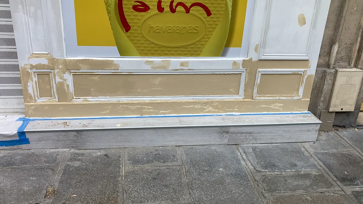 Soubassement de devanture présentant des reprises avant peinture.