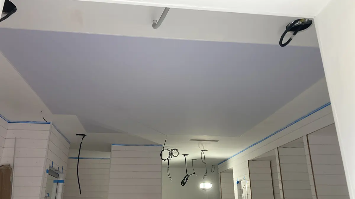 Plafond terminé avec un luminaire et des retombées autour d’une pièce.