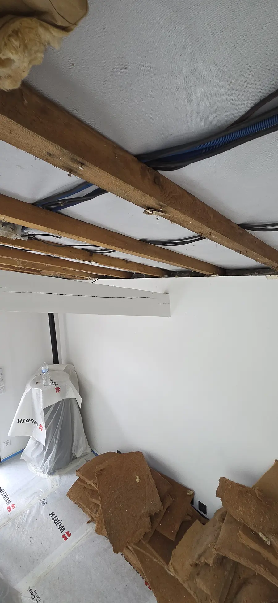 Plafond ouvert avec des éléments de bois et des panneaux retirés.