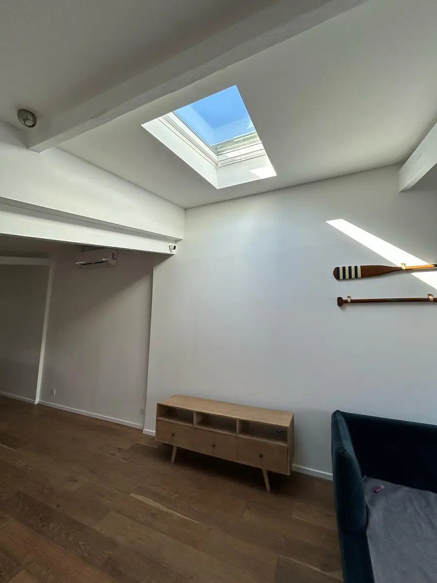 Pièce de vie terminée avec une fenêtre de toit et un plafond blanc.