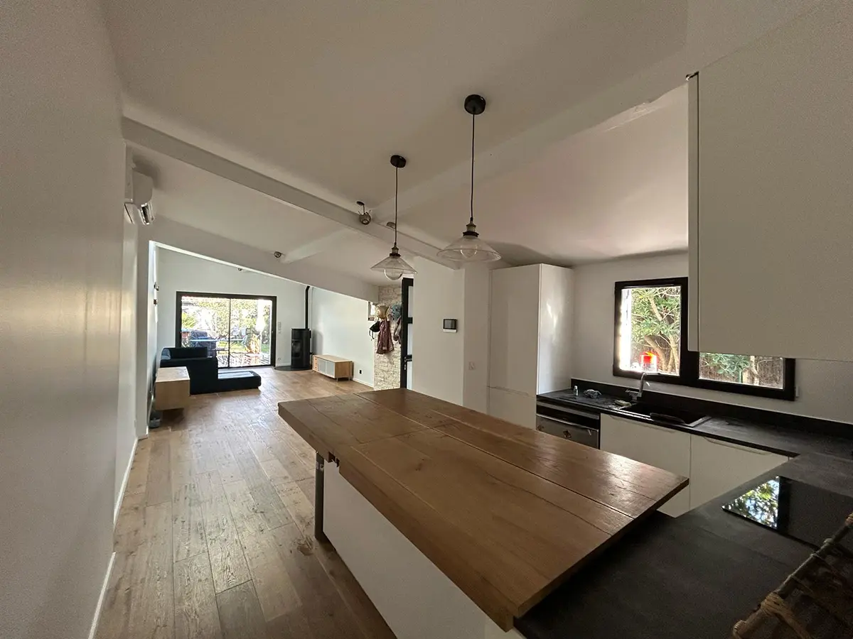 Îlot central en bois sous un plafond blanc avec plusieurs suspensions.