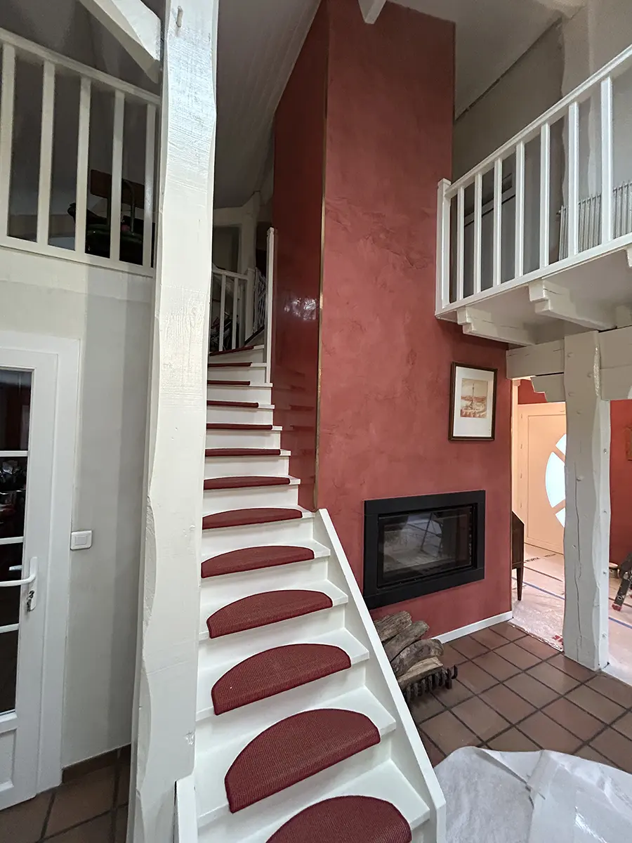 Escalier blanc à marches rouges dans un intérieur à mezzanine.