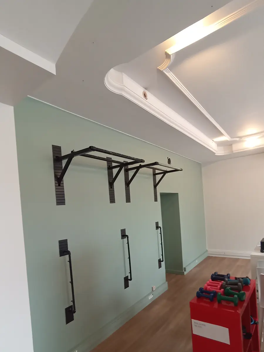 Salle de sport avec un mur vert et des retombées de plafond blanches.
