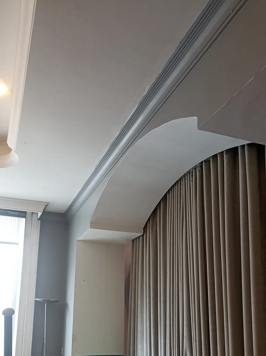 Retombée de plafond arrondie avec une moulure grise et un rideau.