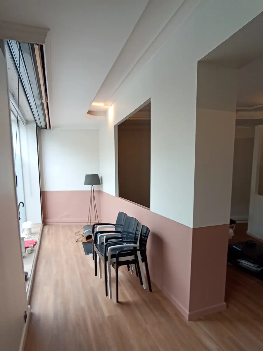 Salle d’attente avec des chaises, des fenêtres et des murs bicolores.