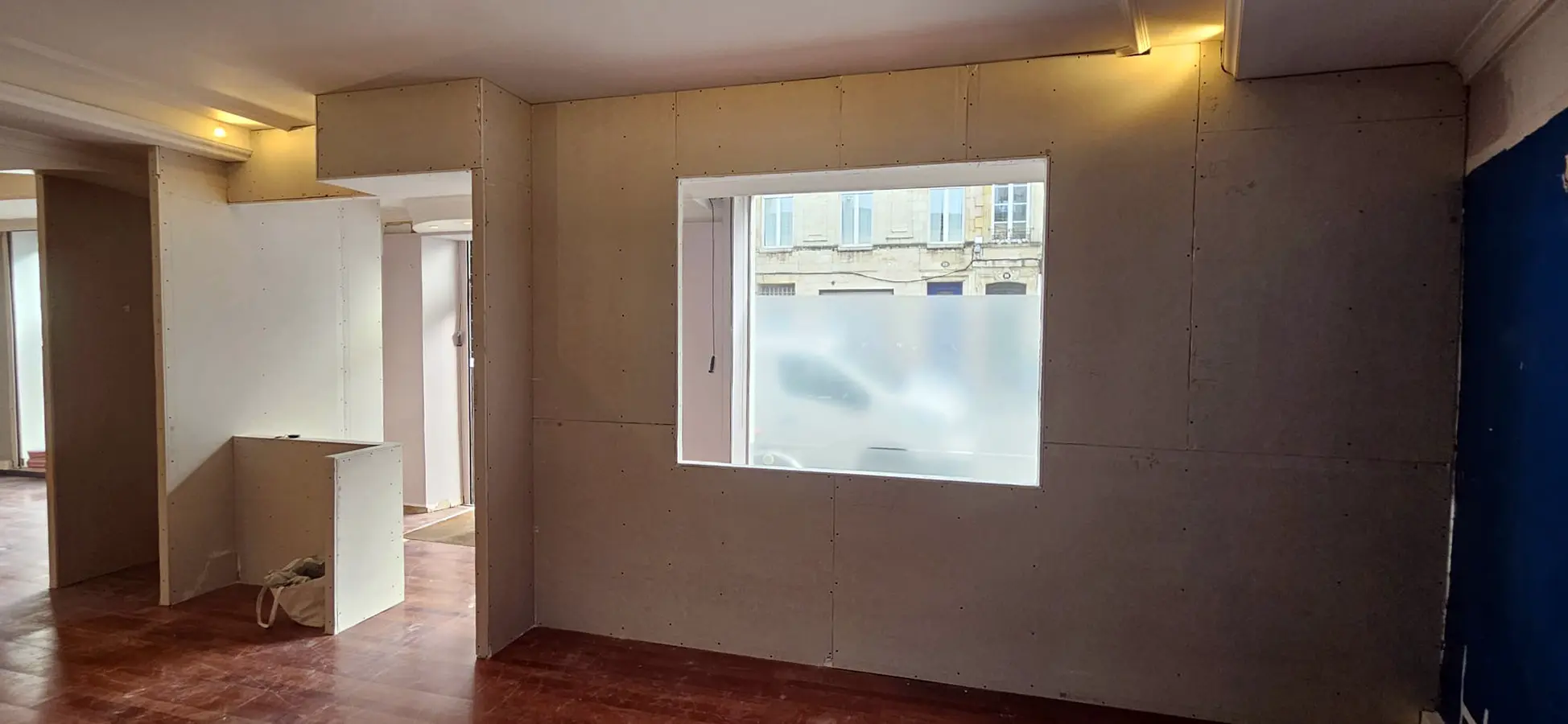 Mur de local professionnel en préparation autour d’une ouverture vitrée.