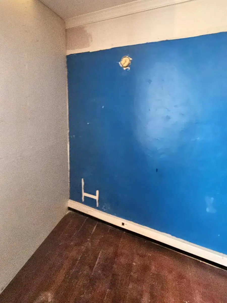 Mur bleu avec des reprises de préparation dans un local en travaux.