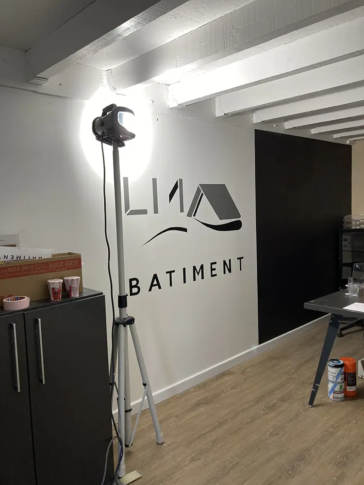 Logo LM Bâtiment en cours de réalisation à côté d’un éclairage de chantier.