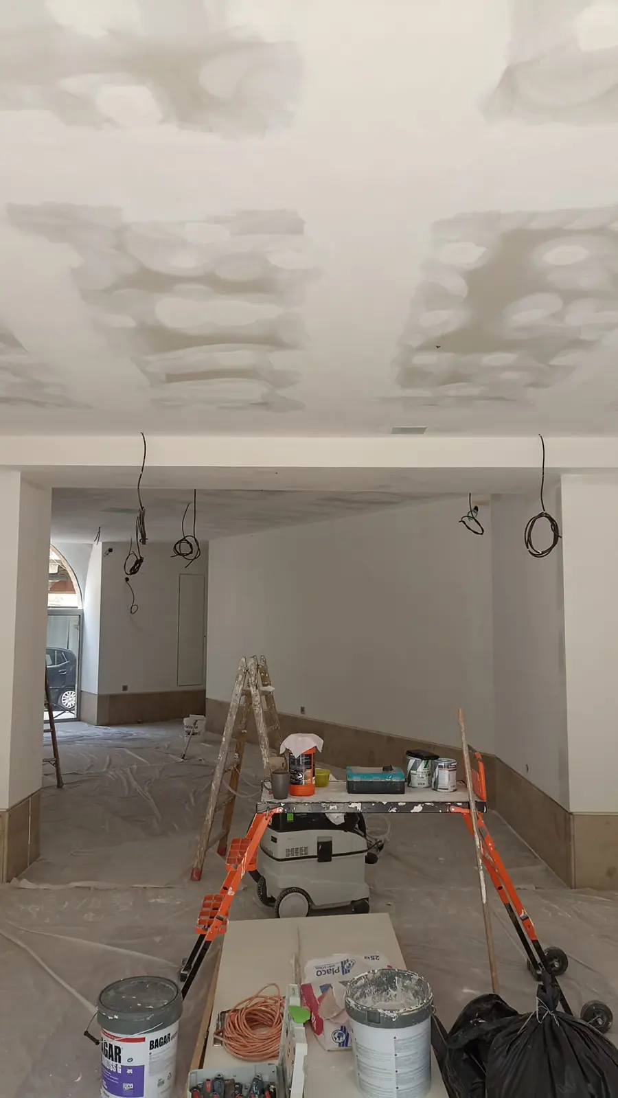 Plafond jointoyé et matériel de chantier dans un local commercial.