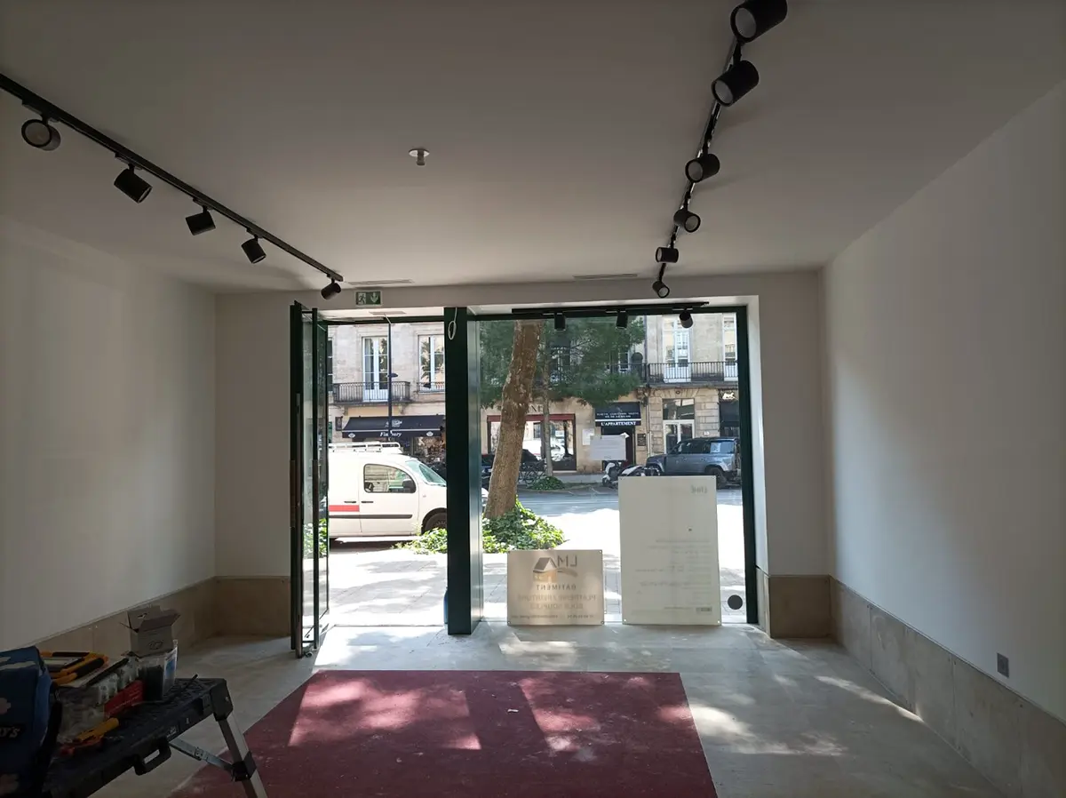 Vue intérieure d’un commerce vers la vitrine et l’entrée sur rue.