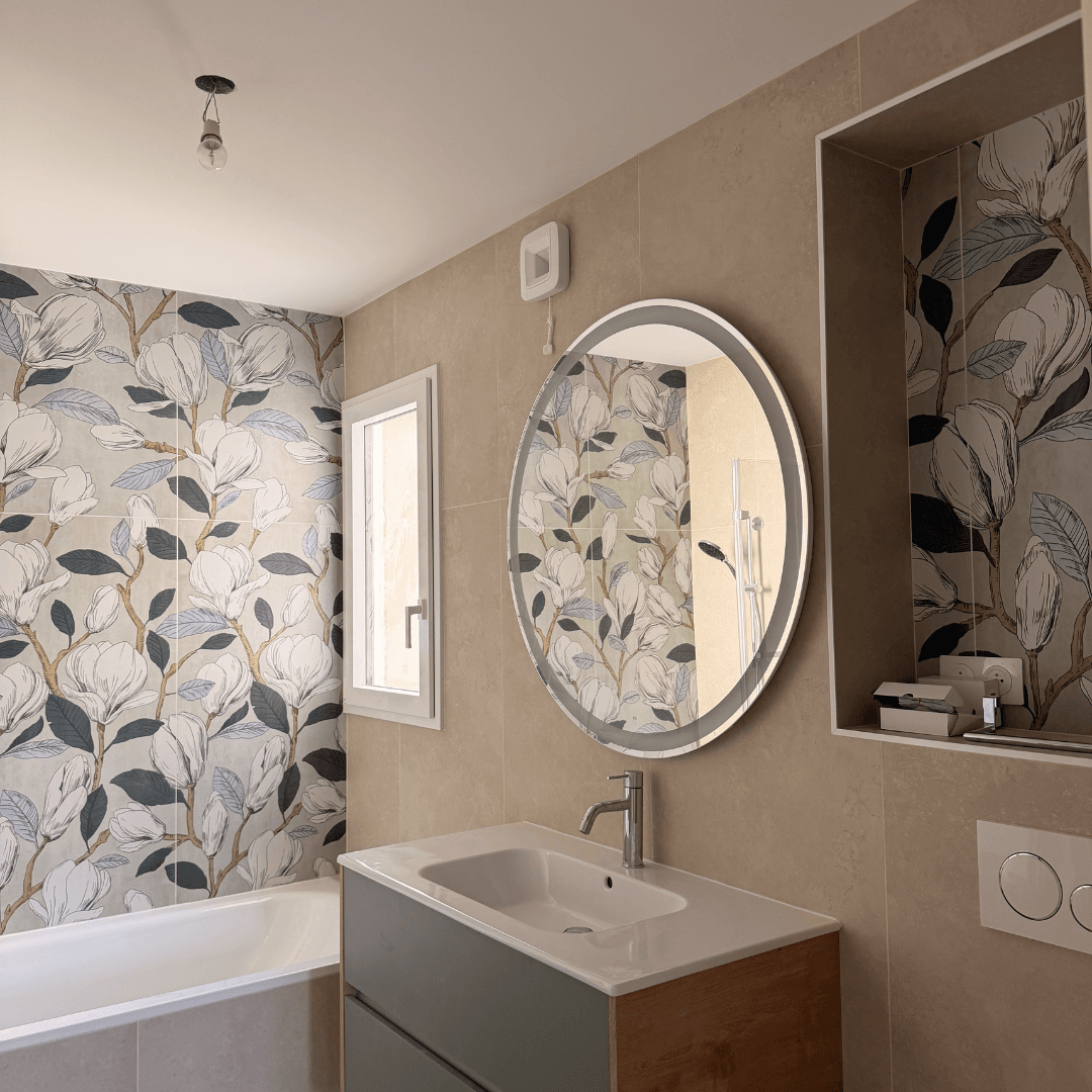 Salle de bain avec un papier peint végétal, un miroir rond et un meuble vasque.