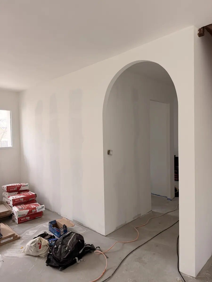 Passage cintré blanc dans un intérieur en rénovation.