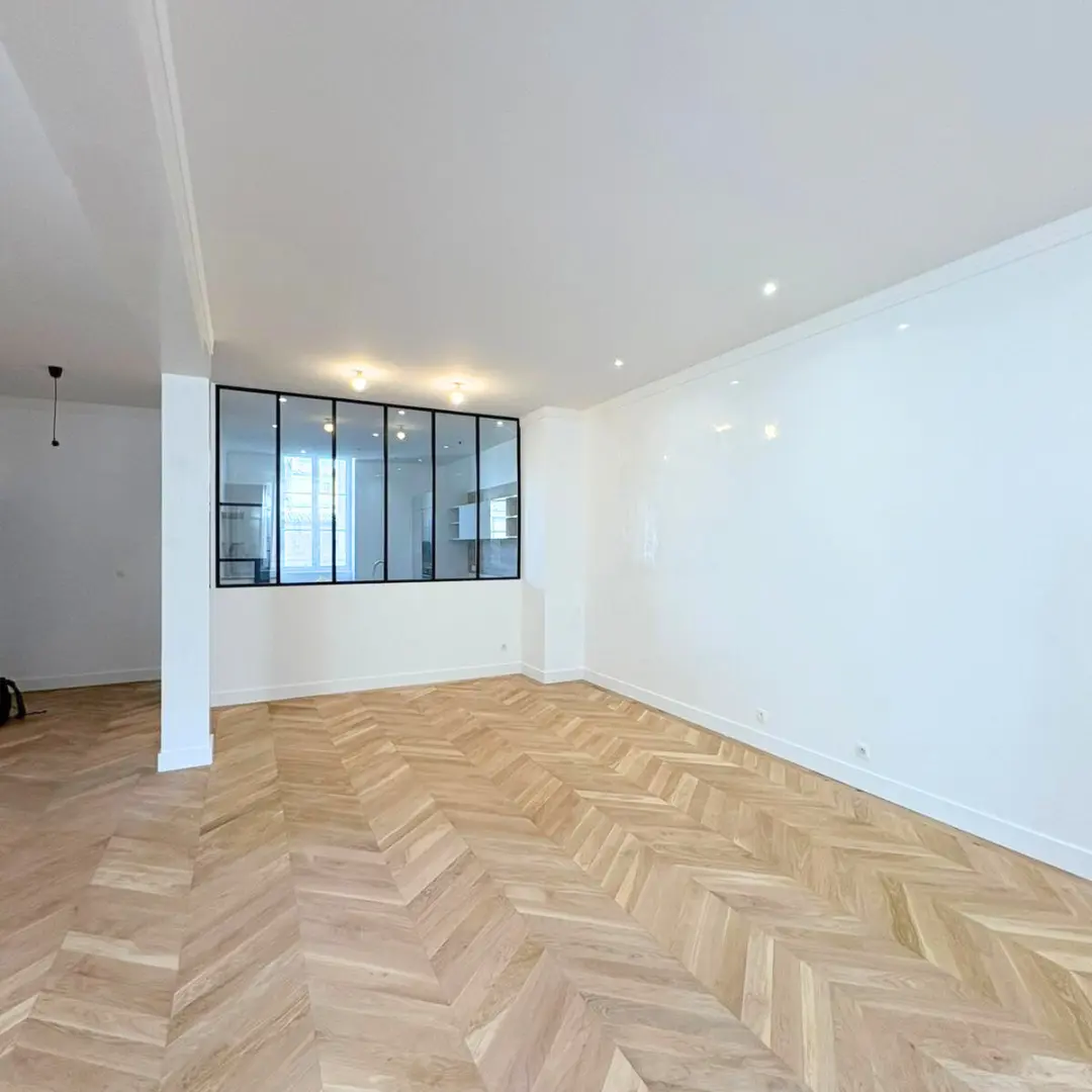 Pièce rénovée avec des murs blancs, une verrière et un sol en chevrons.