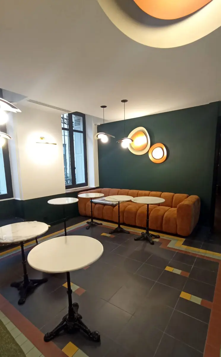 Intérieur de commerce avec un mur vert foncé, un comptoir et des suspensions rondes.