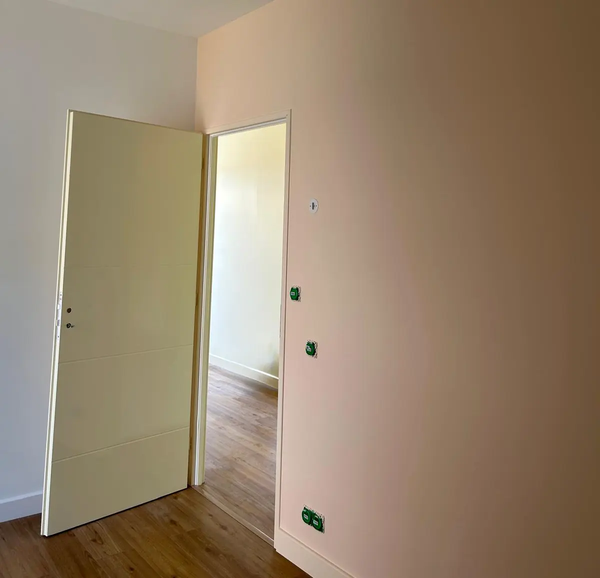 Mur clair et porte blanche avec des boîtiers électriques en attente.