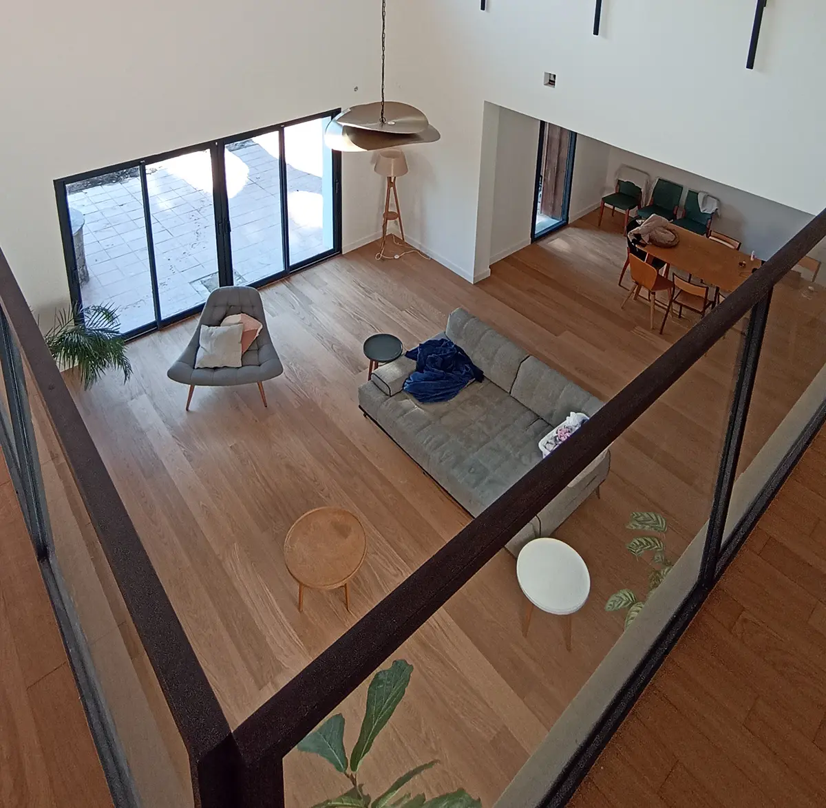 Vue depuis une mezzanine sur une pièce de vie et son sol à effet bois.