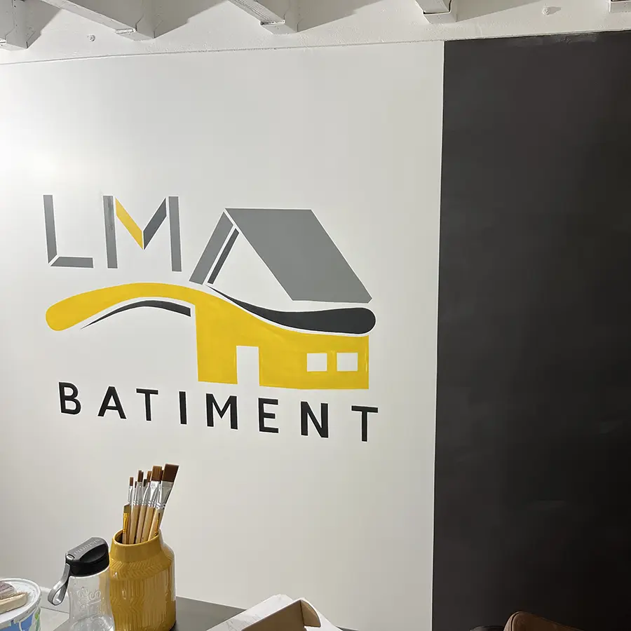 Logo LM Bâtiment peint sur un mur intérieur.